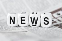 Auf einer Zeitung liegen nebendeinander vier Würfel, die die Buchstaben N, E, W und S anzeigen